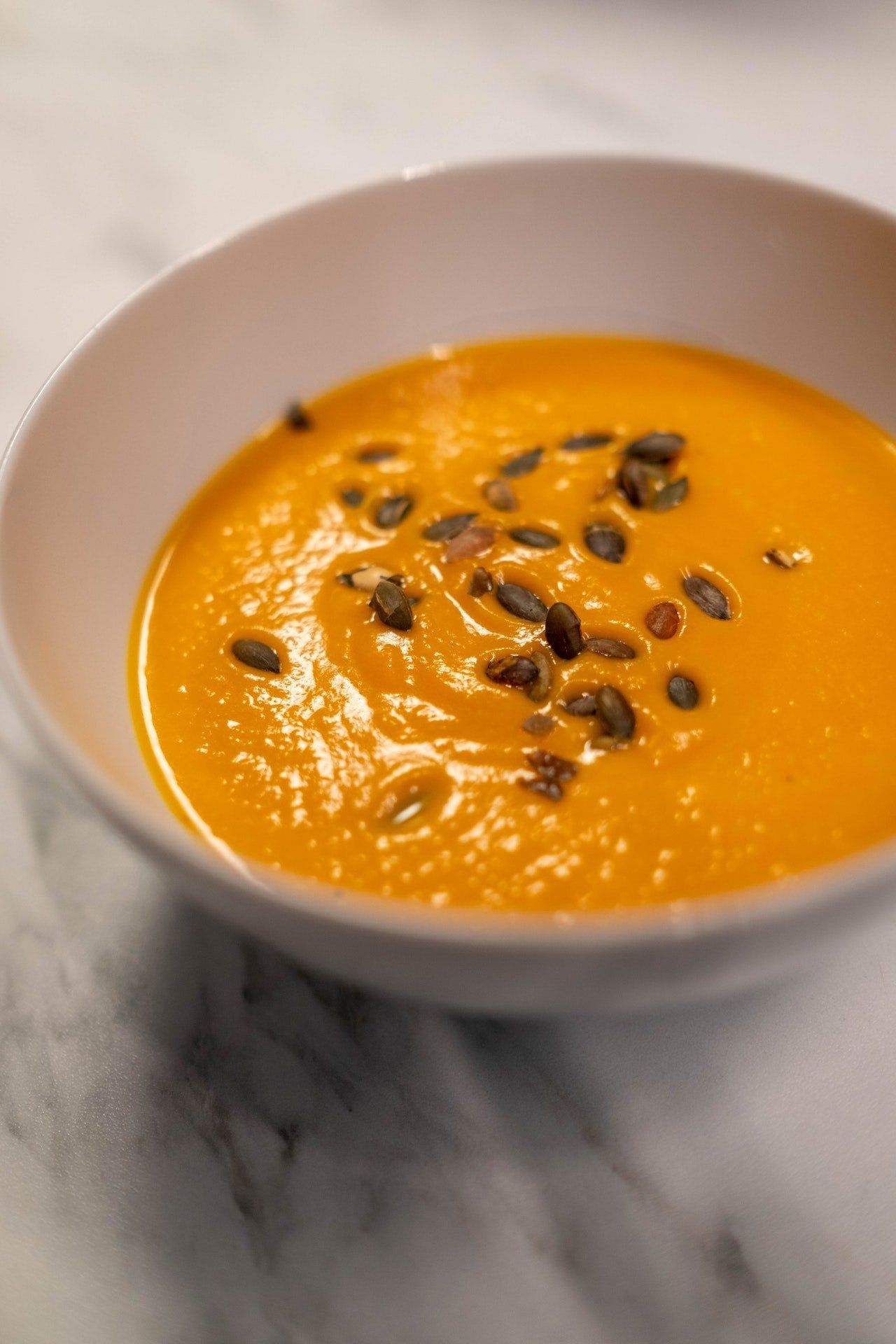 A bowl of soup with pumpkin seeds on top of it