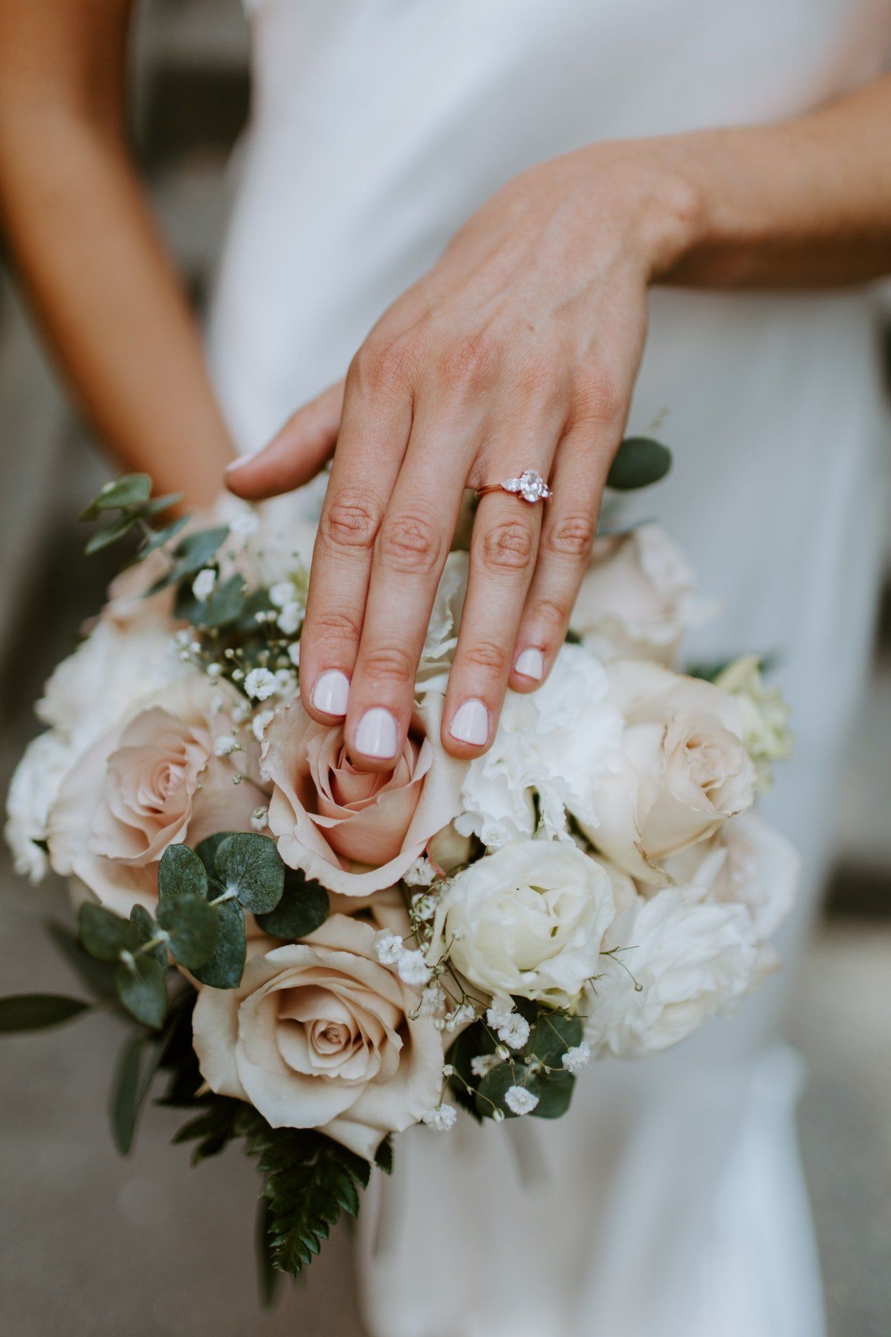 A bride is holding a bouquet of flowers with her ring on her finger.