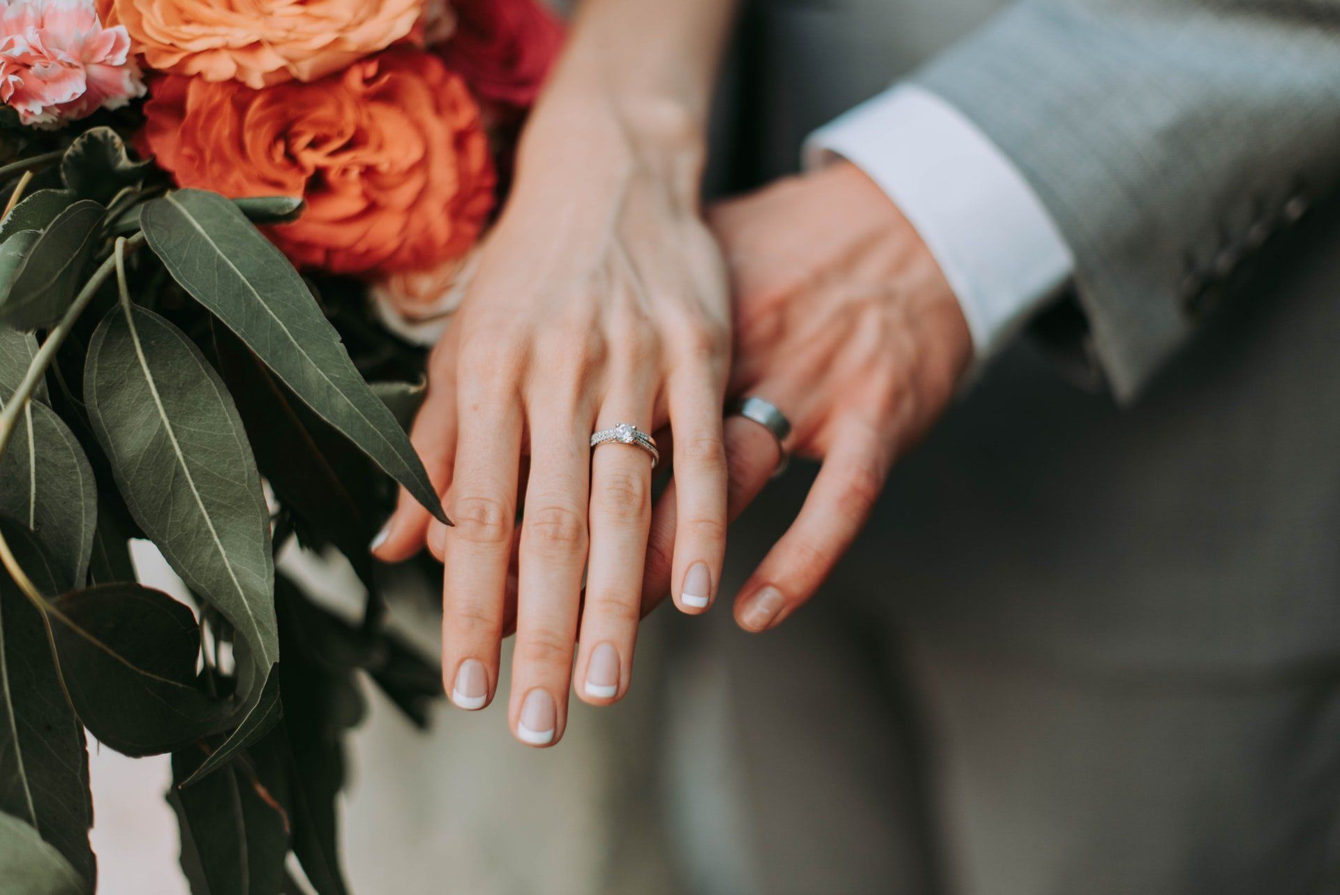 A bride and groom holding hands with their wedding rings on