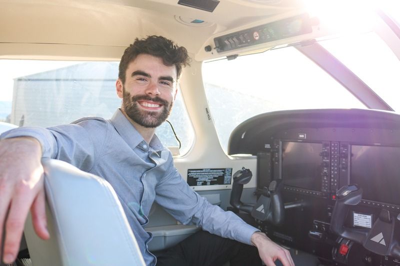 A man with a beard is sitting in the cockpit of an airplane.