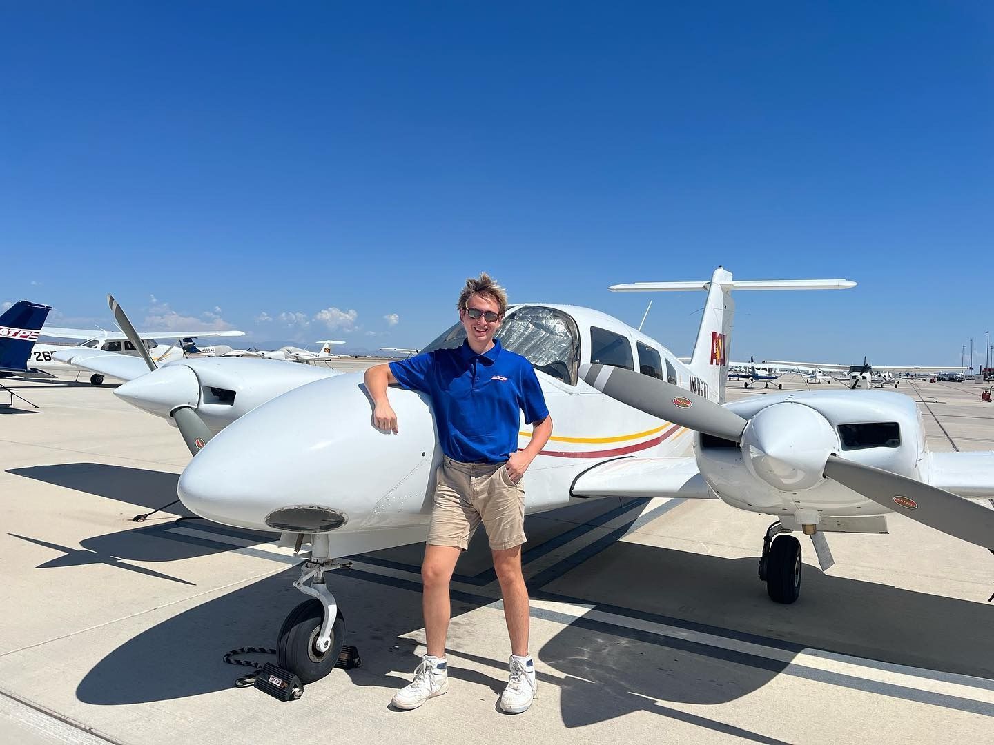 A young man is standing in front of a small plane.
