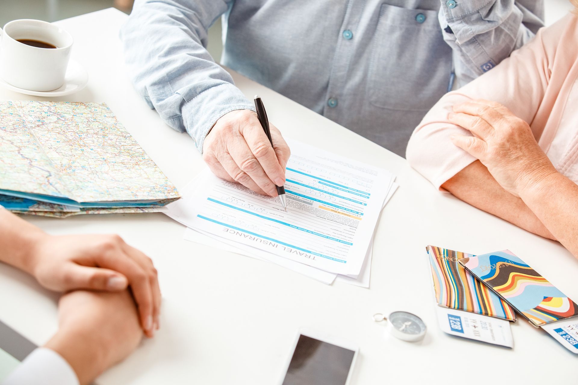 People reviewing paperwork at a table with a notebook, tablet, and coffee cup