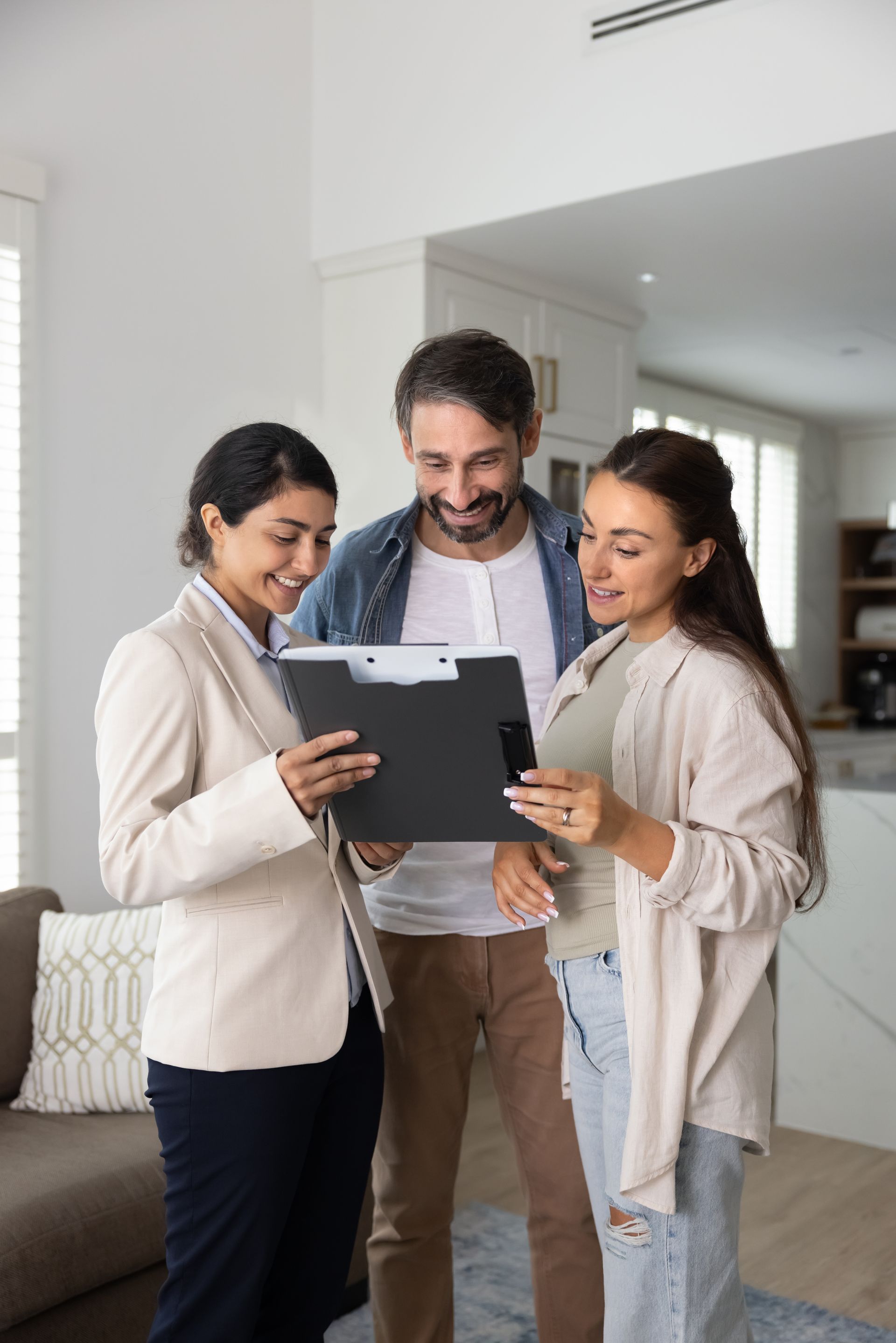 Three coworkers smiling and reviewing a document in a bright office.