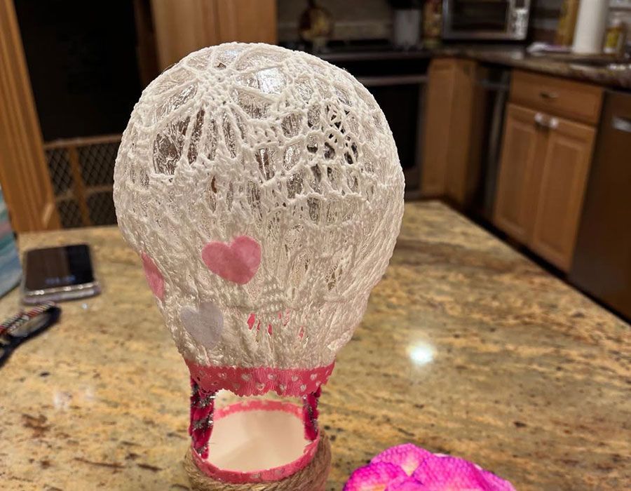 White lace decorative mannequin head with pink heart accents on a kitchen counter