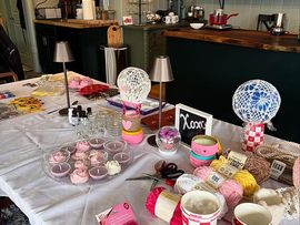 Dessert table with pink treats, cupcakes, lollipops, and decorative centerpieces on a white tablecloth