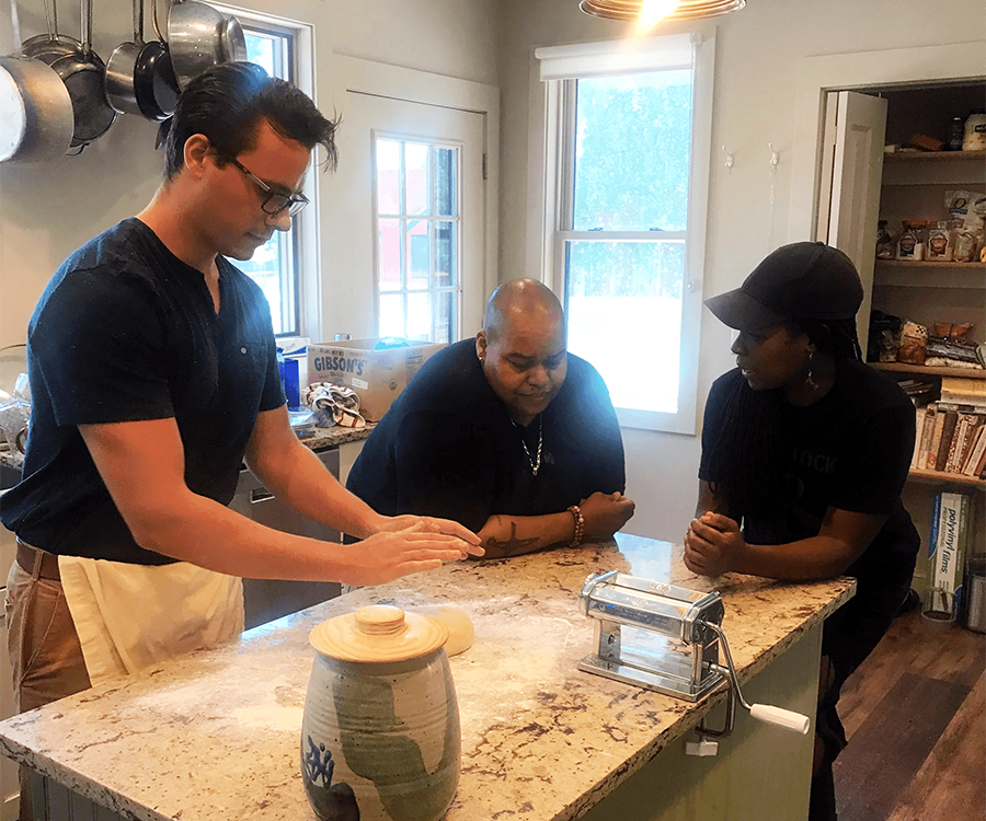 Three people preparing food together in a bright kitchen