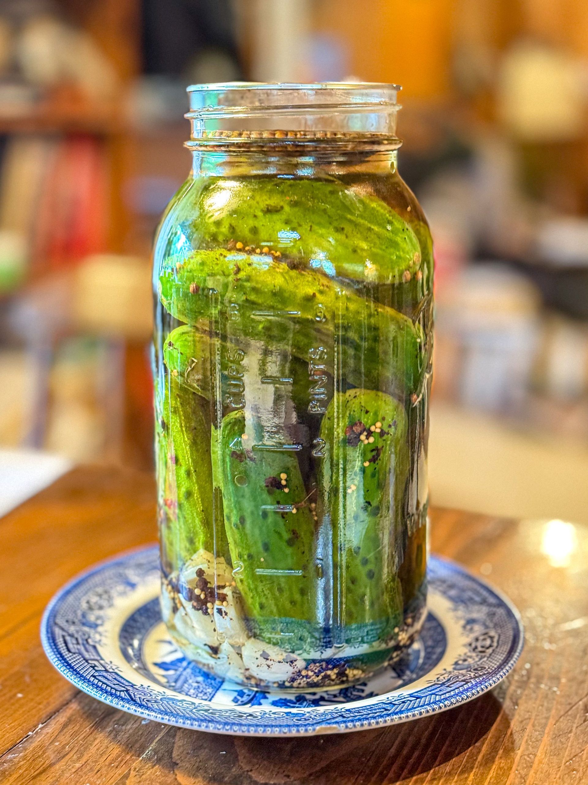 Green painted glass jar on a blue patterned plate on a wooden table, with a blurred café background