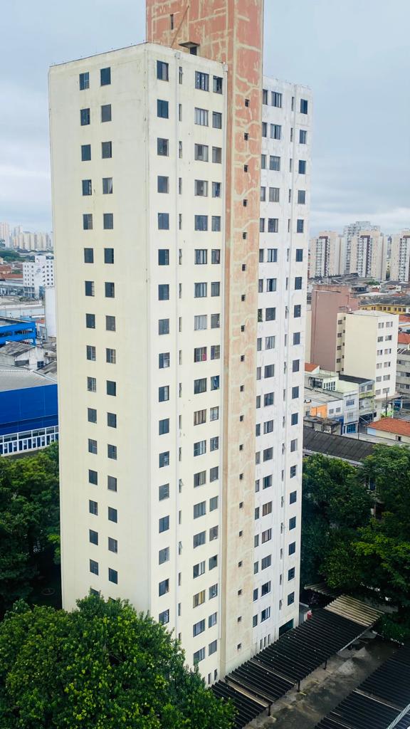 Um edifício alto com muitas janelas está cercado por árvores em uma cidade.