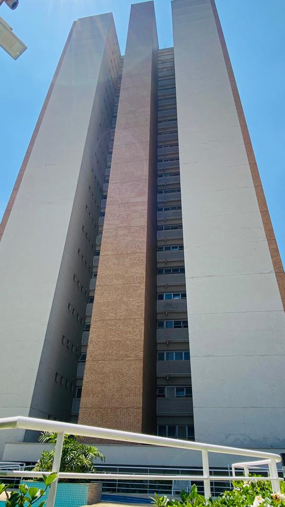 Um edifício alto com uma piscina na frente.