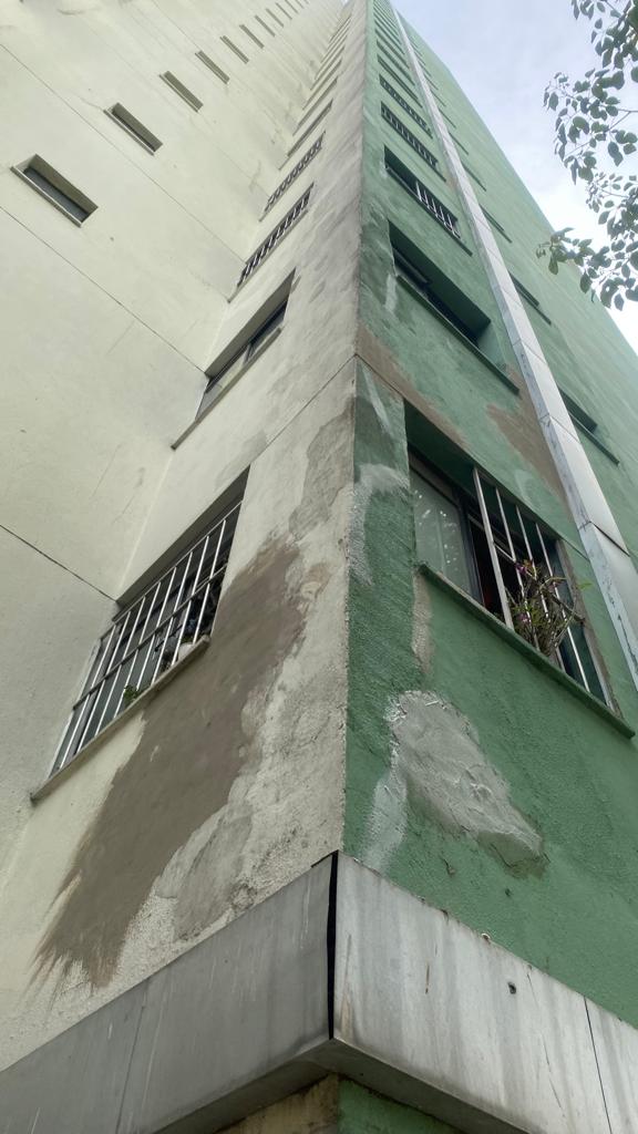 Um prédio verde e branco com uma escada subindo pela lateral.