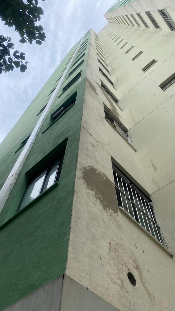 Olhando para um edifício alto com uma fachada verde e branca.
