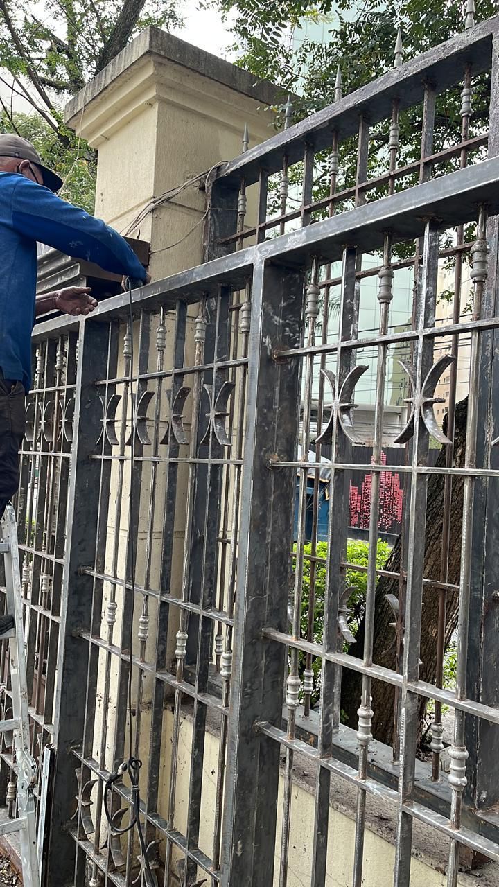 Um homem está em pé no topo de uma cerca de ferro forjado.