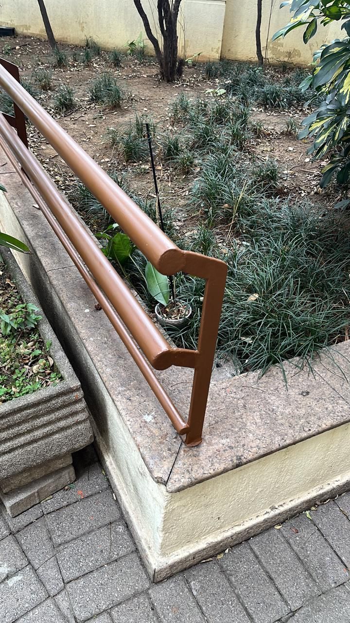 Um corrimão de madeira está ao lado de um vaso em um jardim.
