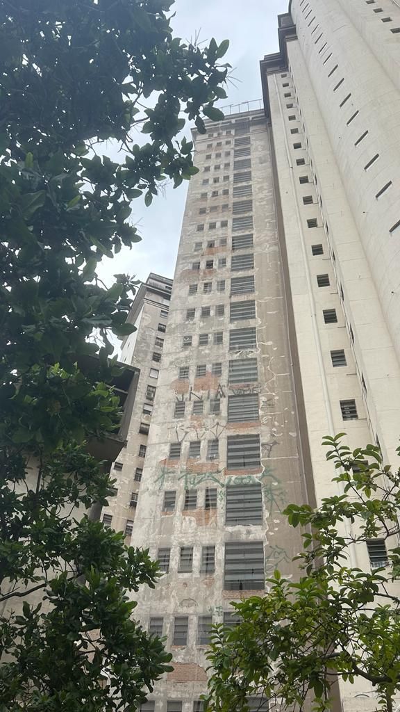 Um edifício alto com muitas janelas cercado por árvores.