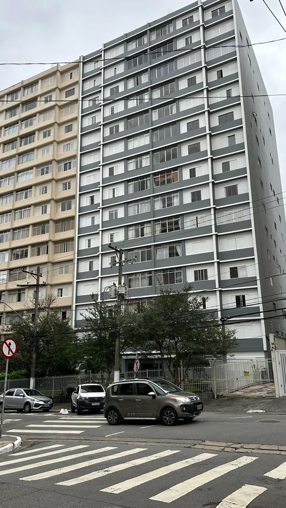 Um carro está dirigindo pela rua em frente a um prédio alto.