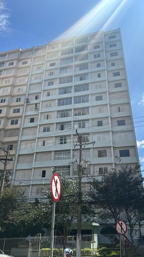 Um prédio alto com muitas janelas e uma placa de proibido estacionar na frente.