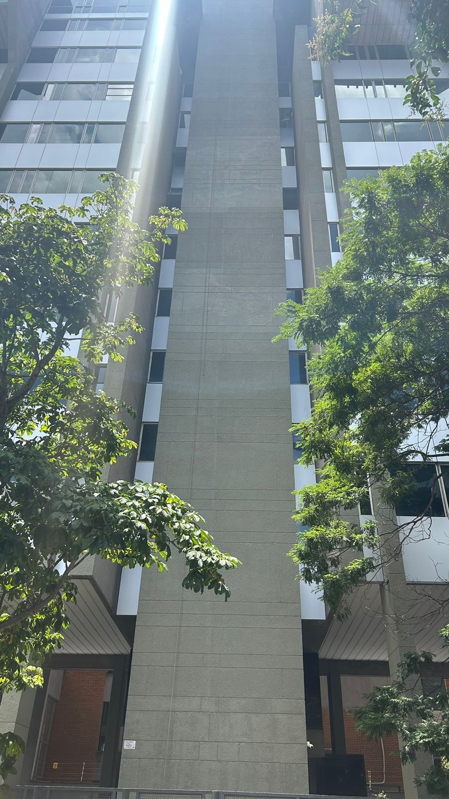 Um prédio alto com muitas janelas e árvores na frente
