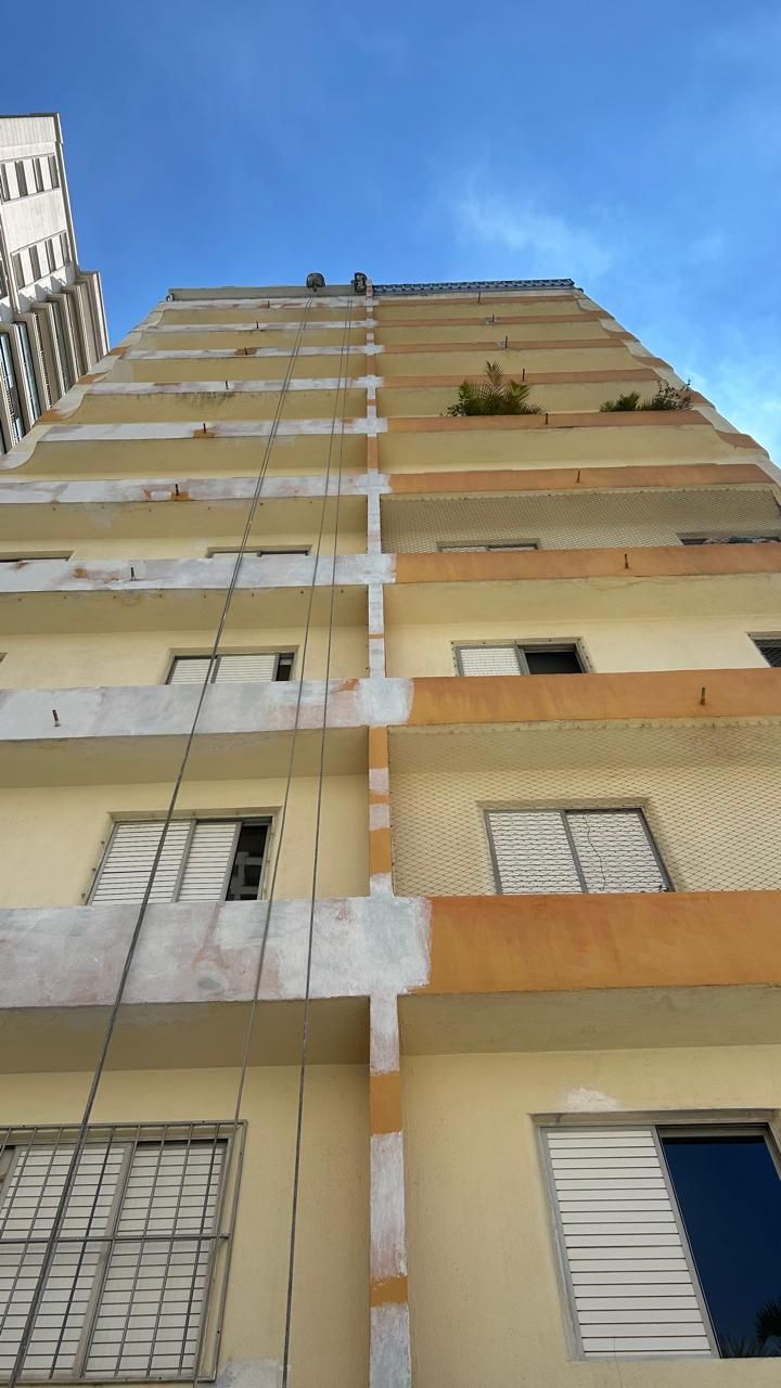 Olhando para um prédio alto com um céu azul ao fundo.