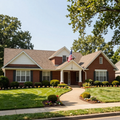 Single-story brick house with manicured lawn, curved walkway, and an American flag by the front porch