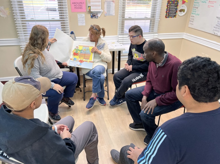 Small group in a circle discussing a colorful board game in a bright room