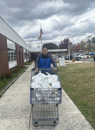 Person pushing a cart full of bags along a sidewalk beside a building under cloudy skies