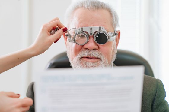 An elderly man is getting his eyes checked by an ophthalmologist.