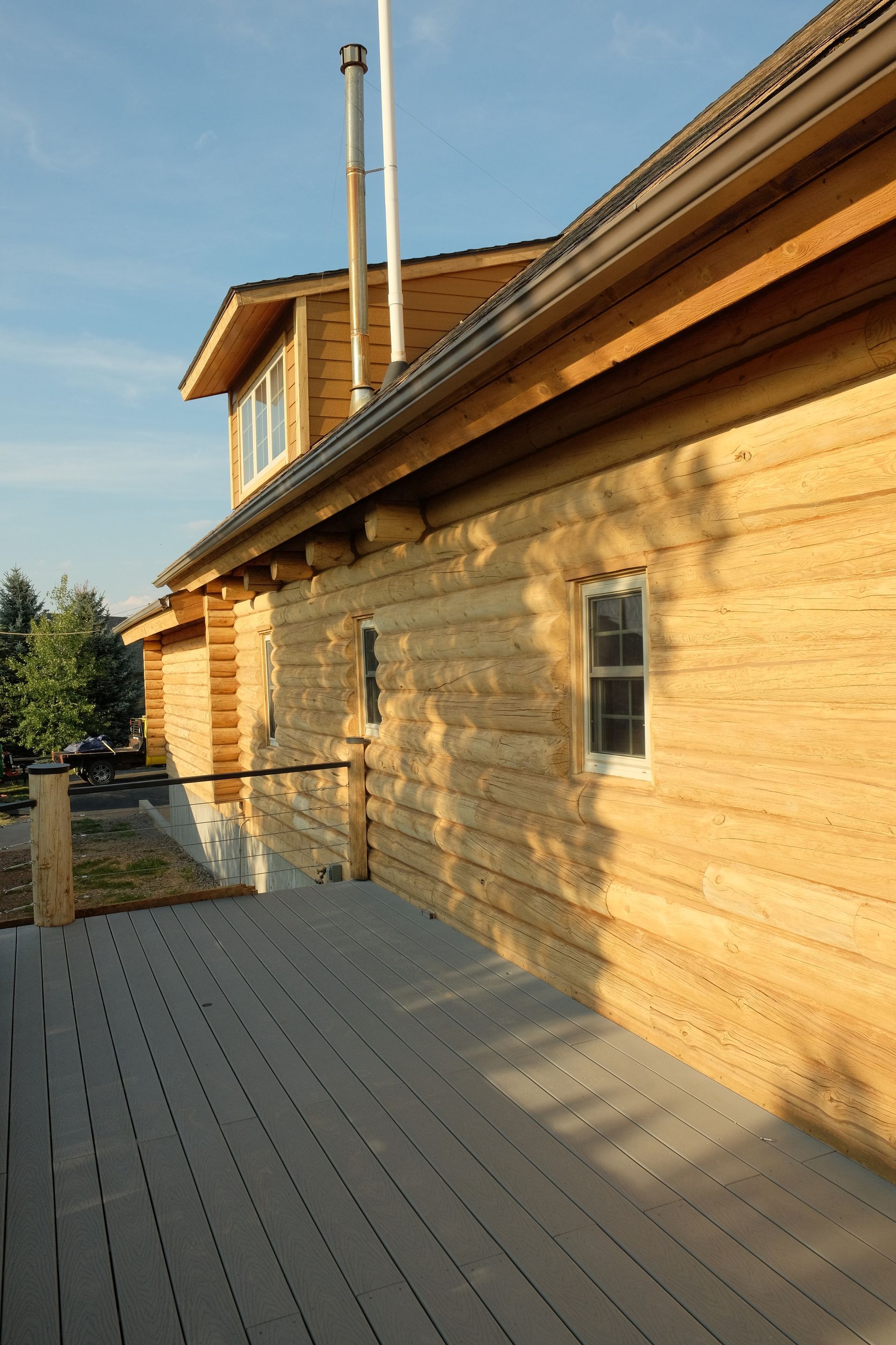 Close-up of a log cabin wall with mountain and open field in the background