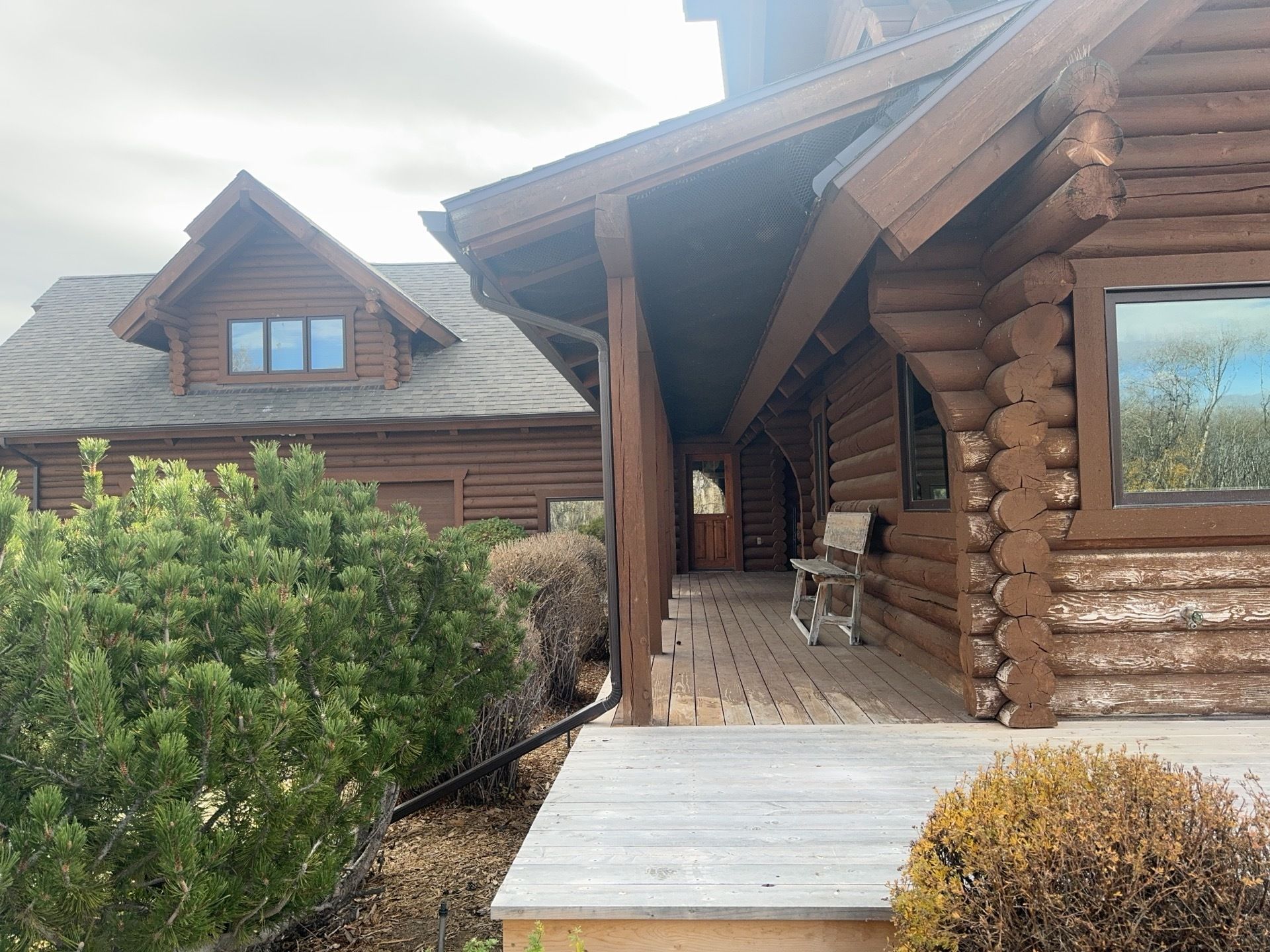Log cabin with white logs and brown roof under a clear blue sky, seen from the front.