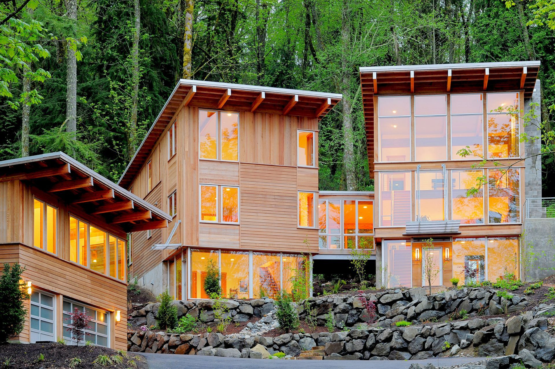 A house with a lot of windows is surrounded by trees