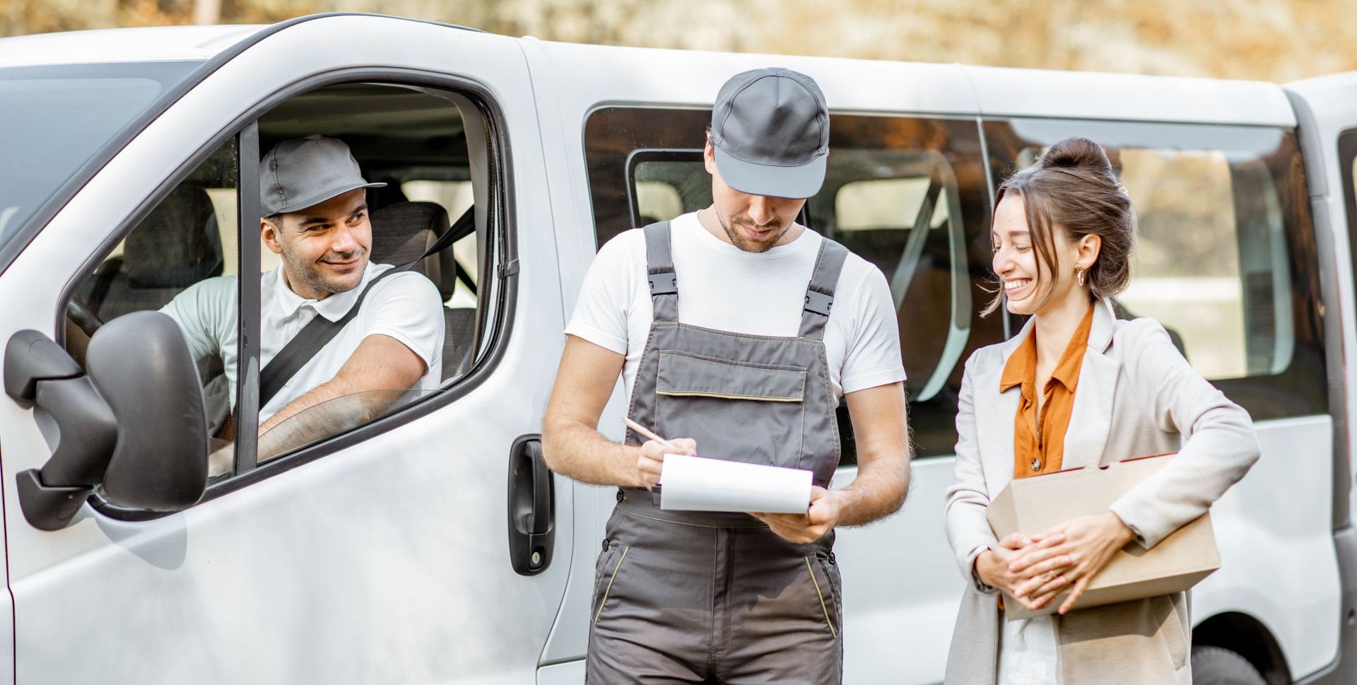 A delivery man is standing next to a woman in front of a van.