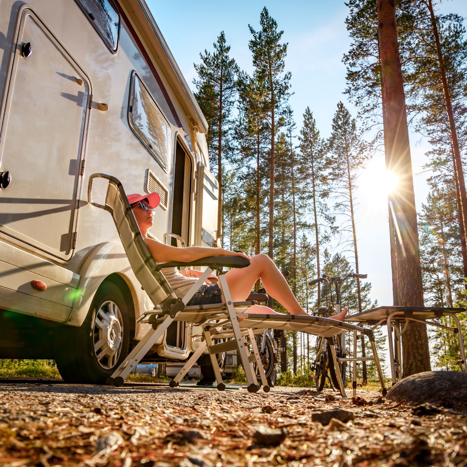 A woman is sitting in a chair in front of a rv.
