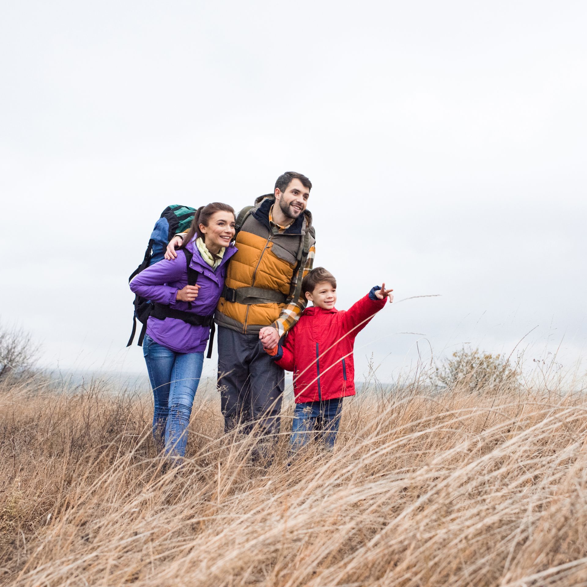 A family is walking through a field of tall grass.