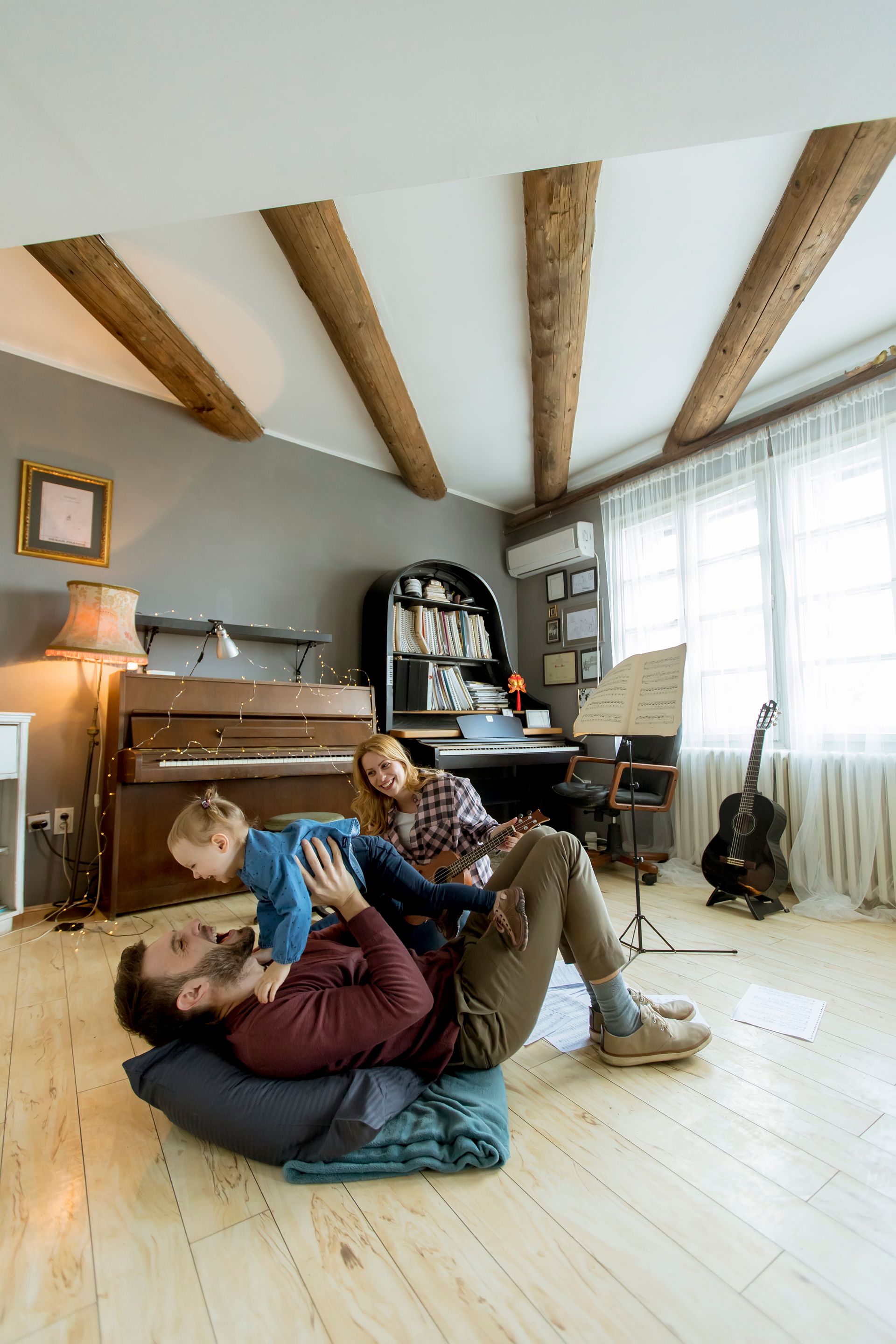 A man is laying on the floor playing with a child in a living room.