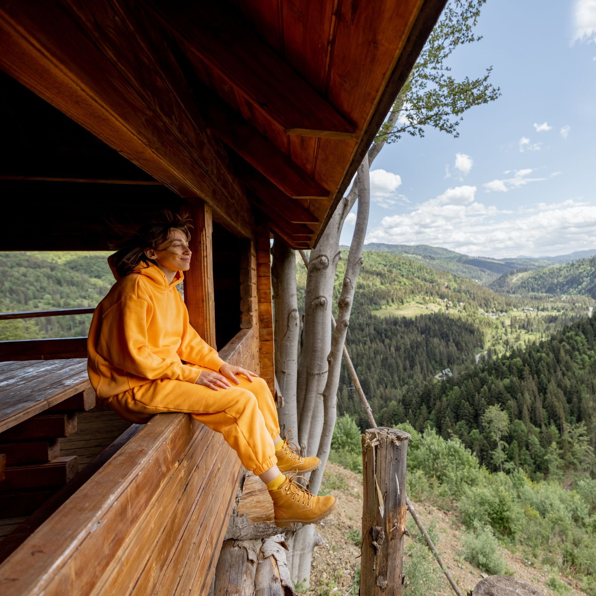 A woman sits on a balcony overlooking a valley