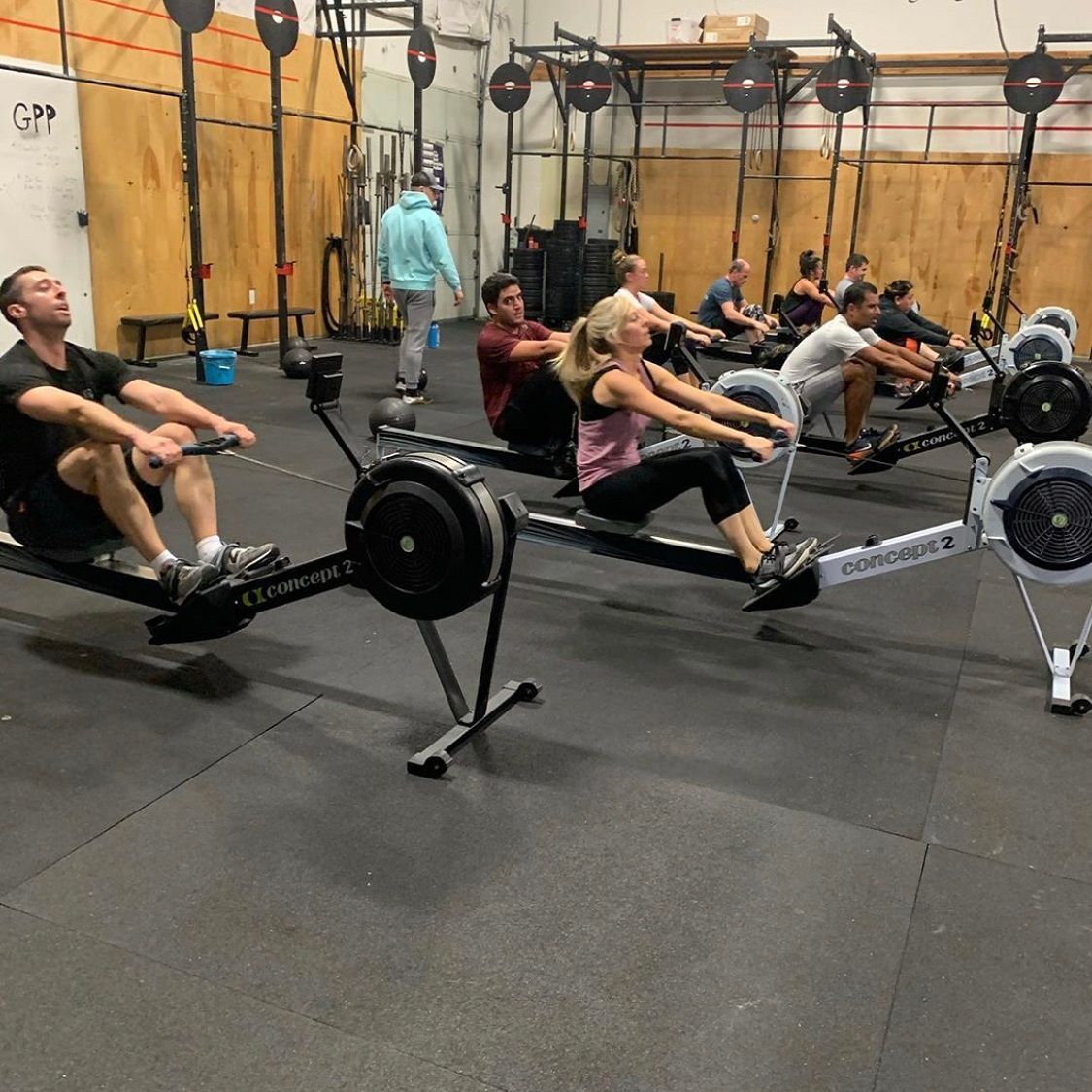 A group of people are rowing rowing machines in a gym.