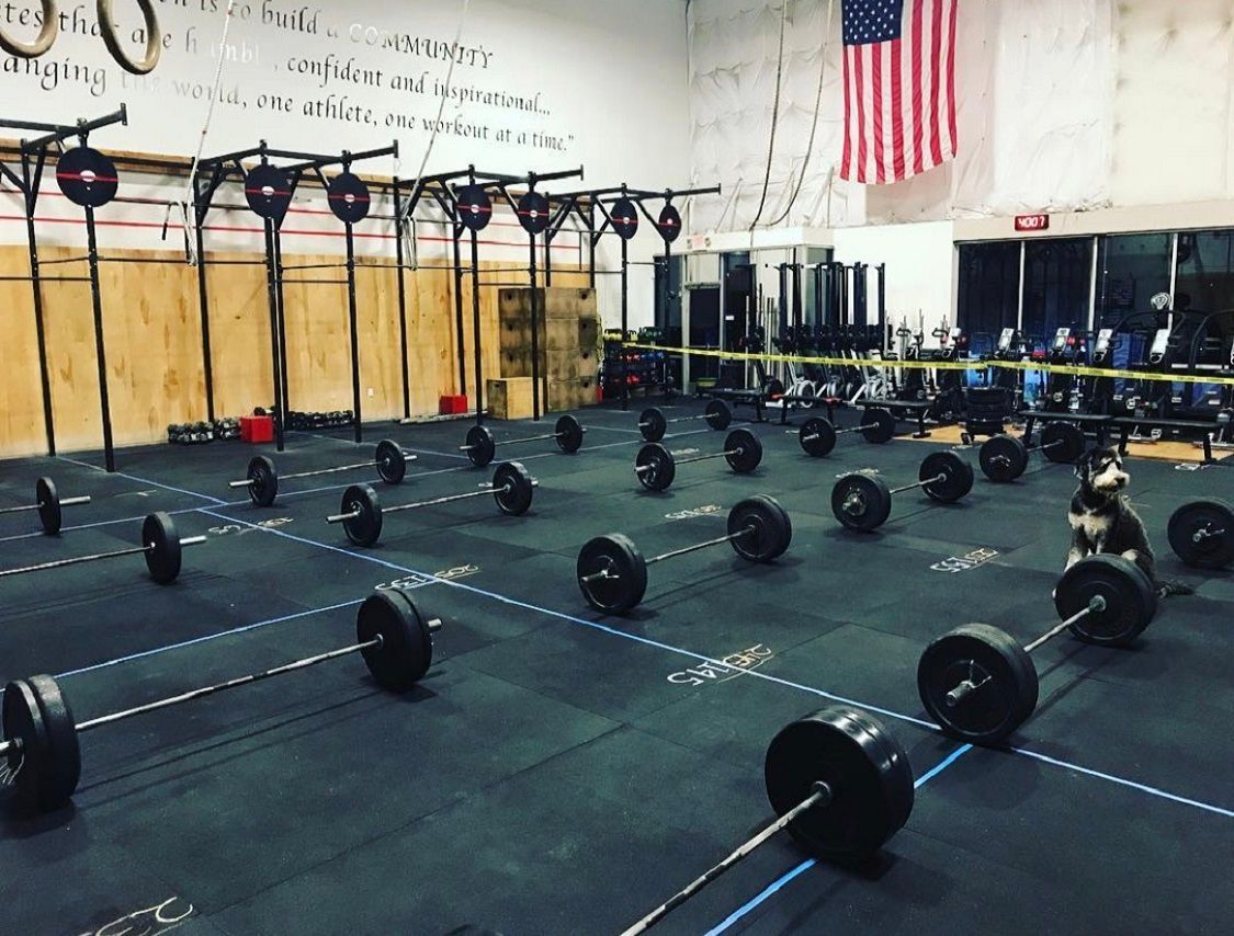 A gym with a lot of barbells on the floor and an american flag on the wall.