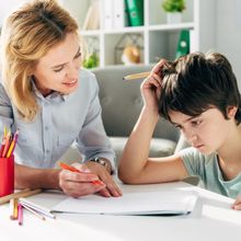 A woman is helping a young boy with his homework.