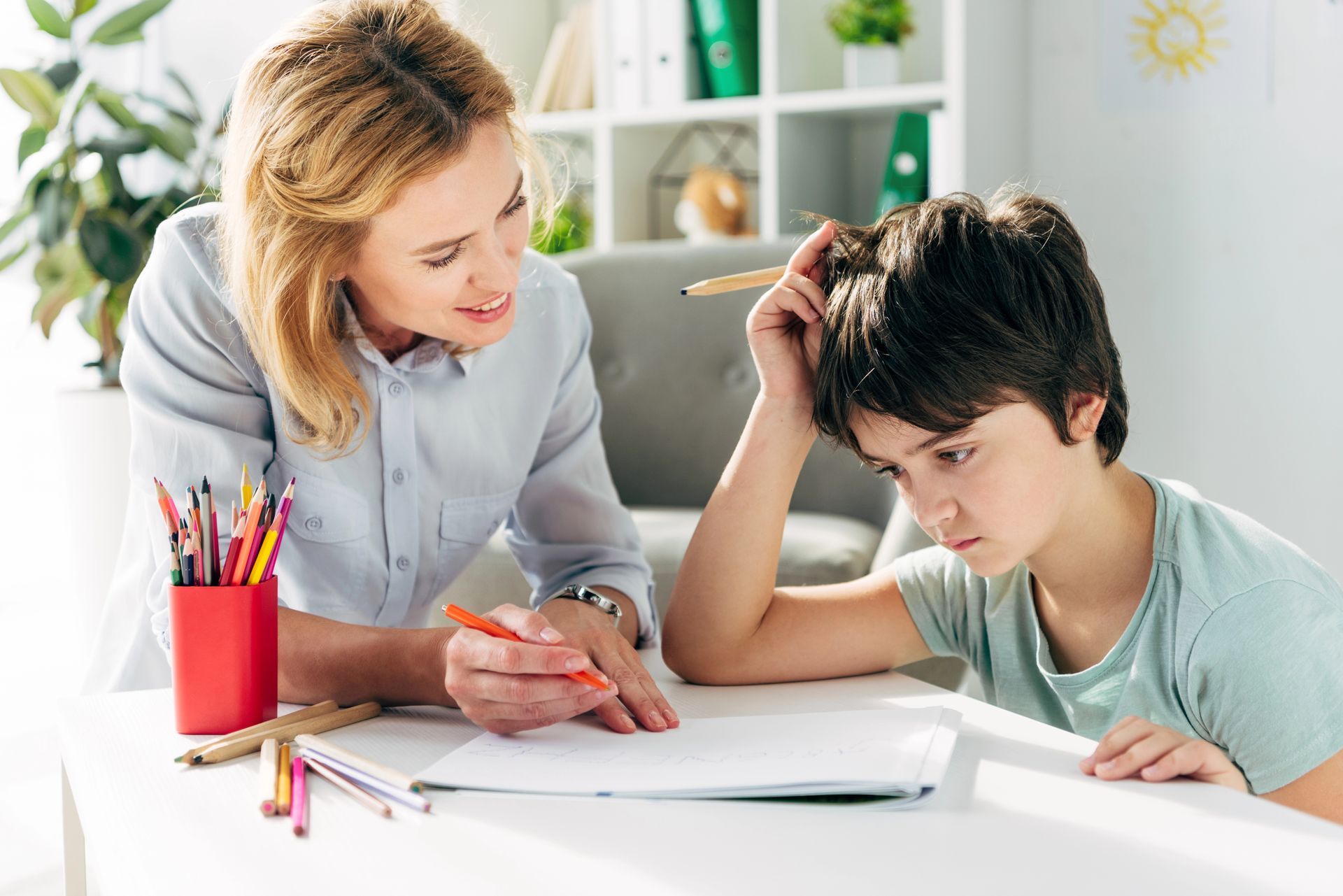 A woman is helping a young boy with his homework.