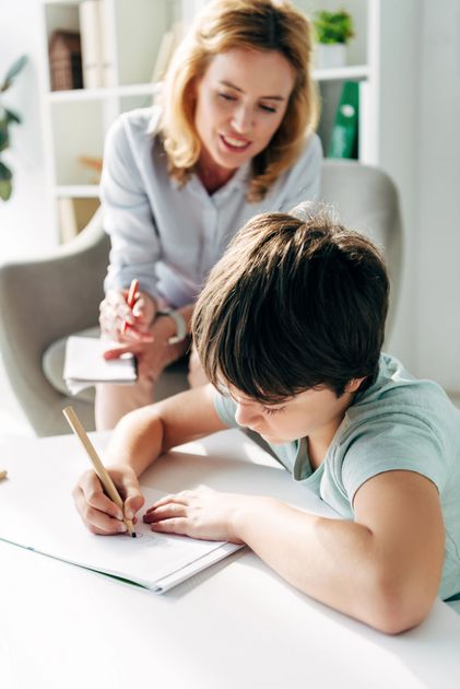 A woman is helping a young boy with his homework.