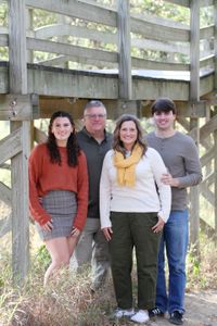 A family is posing for a picture in front of a wooden bridge.