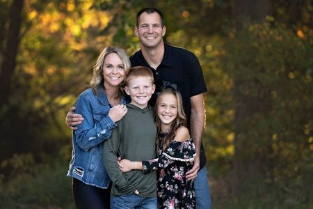 A family is posing for a picture in the woods.
