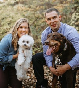 A man and a woman are posing for a picture with their dogs.