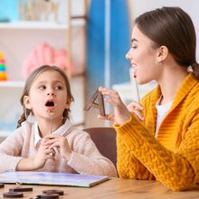 A woman and a little girl are sitting at a table playing with letters.