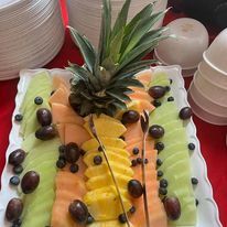 Fruit platter with a pineapple, cantaloupe, honeydew, and grapes.