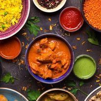 Overhead view of various Indian dishes in small bowls; includes rice, curries, and sauces.