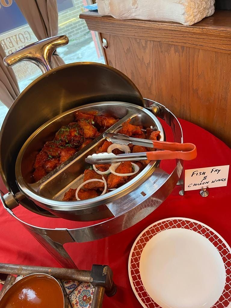 Buffet with fried food, including onion rings and a red sauce, in a silver warmer.