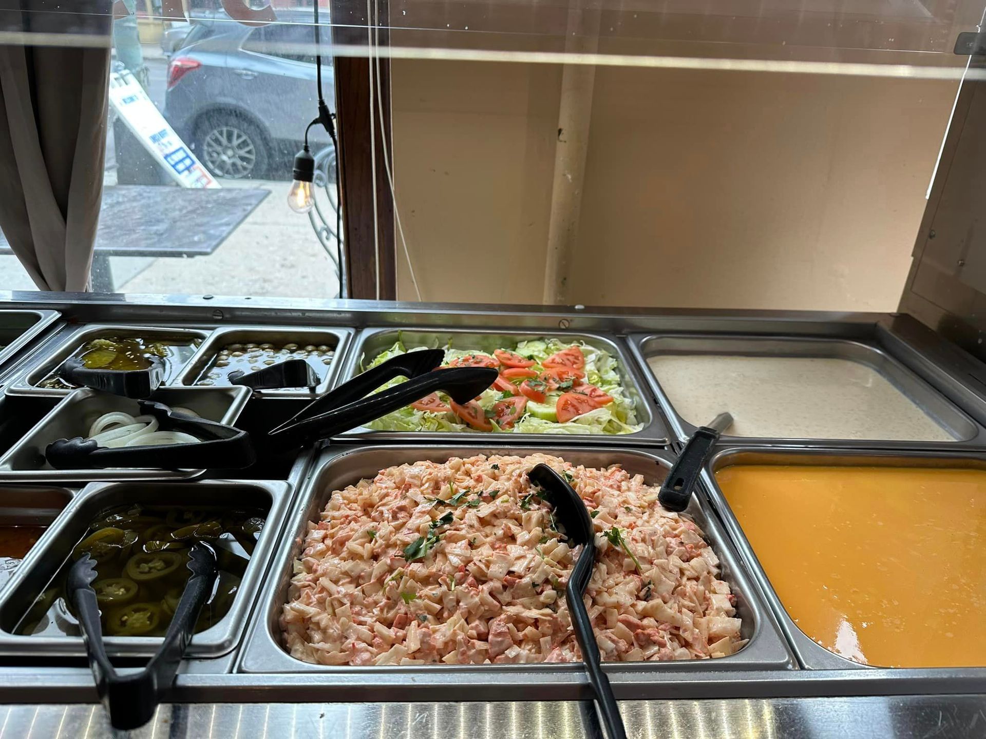 A buffet-style food display with various dishes, including salads and sauces, in metal trays.