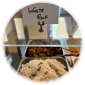 Food display with white rice and other dishes behind a glass.