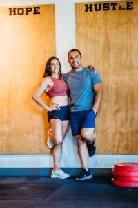 Man and woman lean against wooden wall,