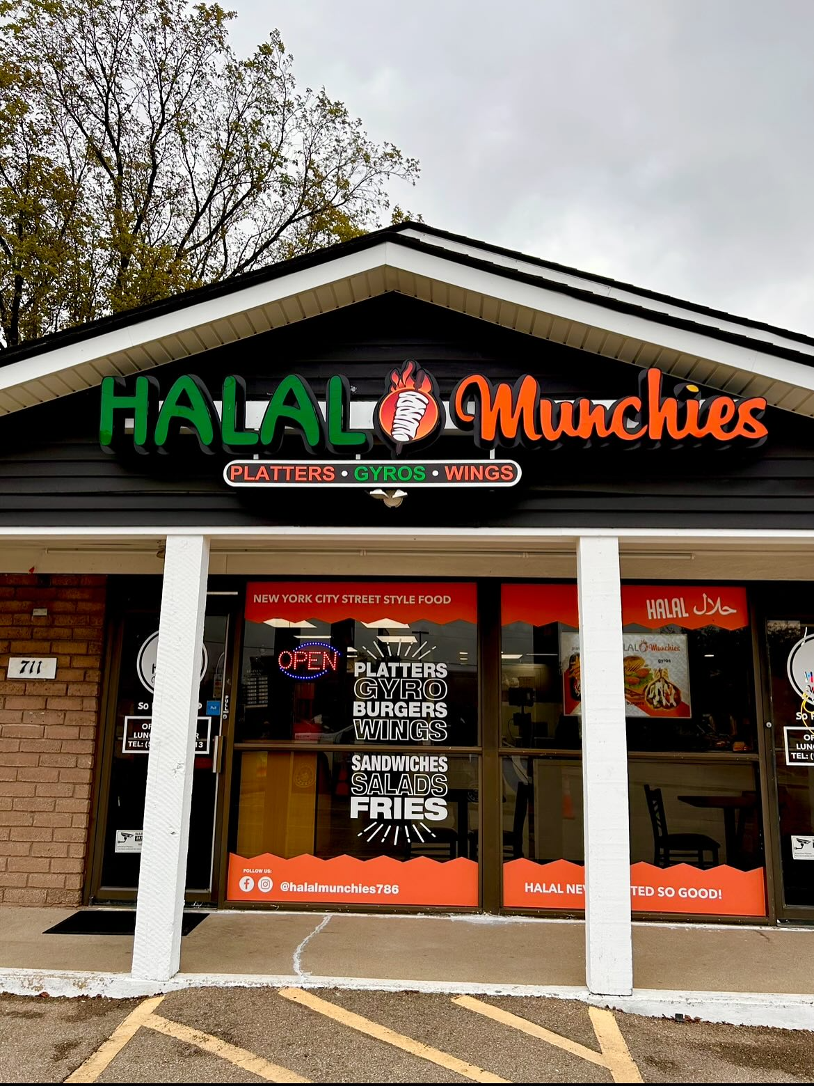 Halal Munchies restaurant exterior with sign, door and window displays, brick and concrete facade.